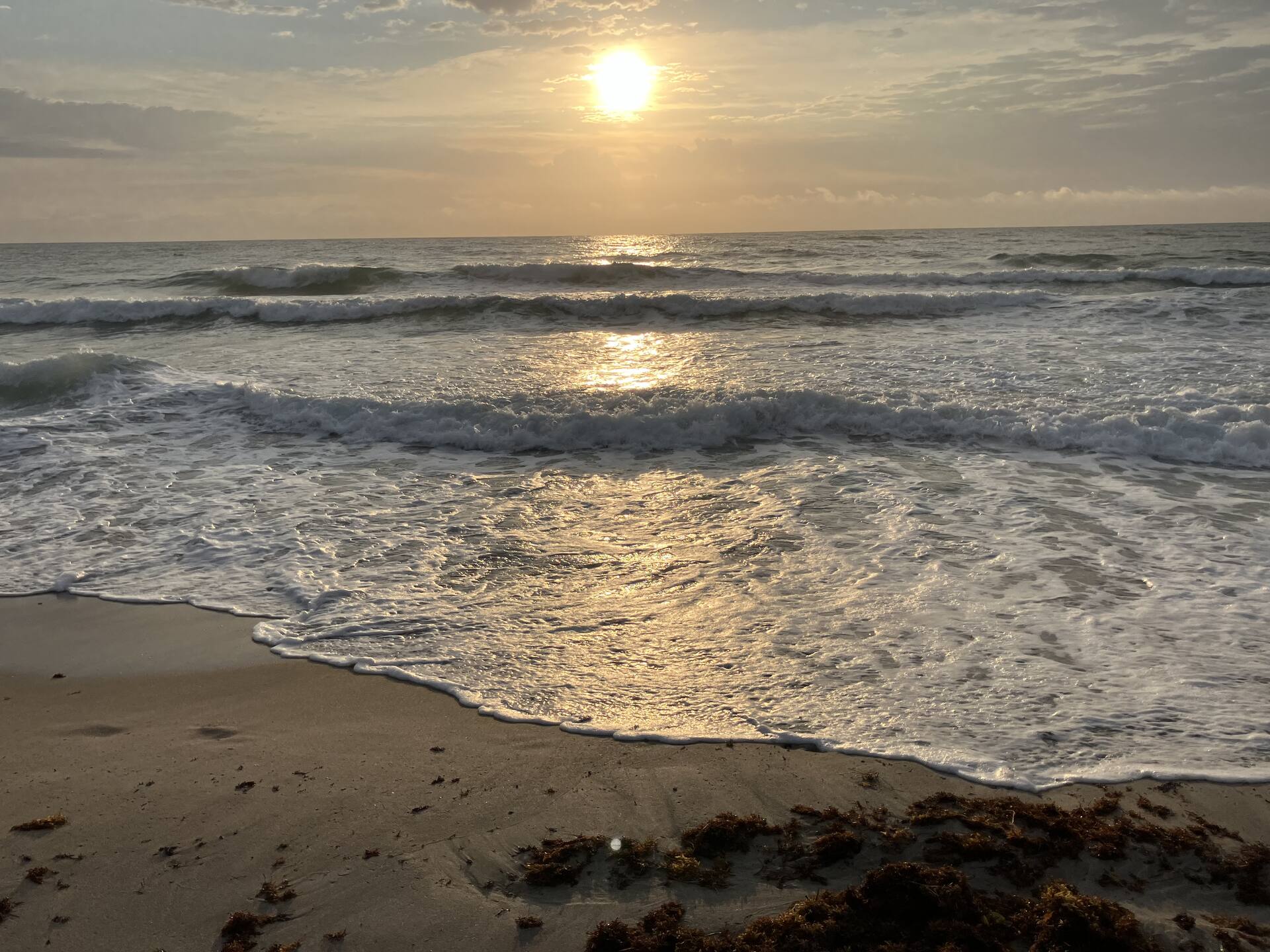 Sunrise over the Atlantic, the low sun laying a golden path across the water as waves wash up the sand.